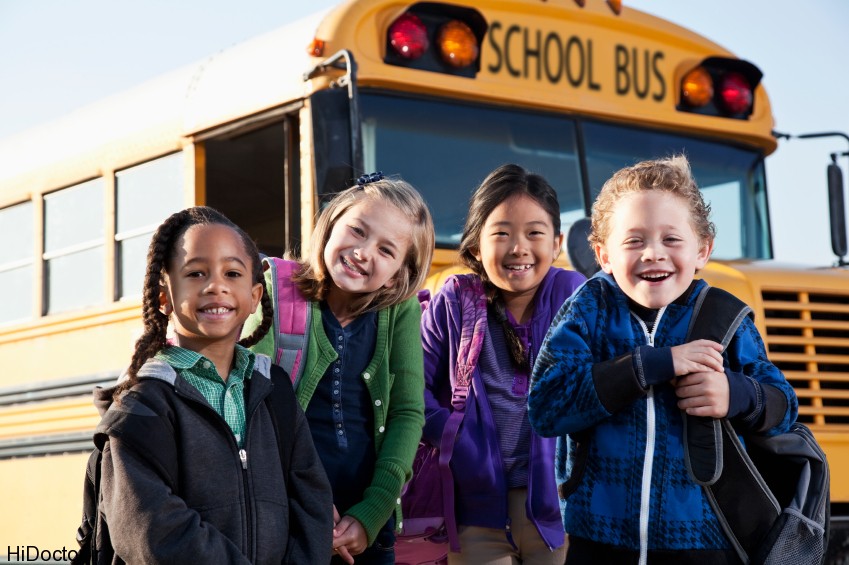 Children standing outside school bus