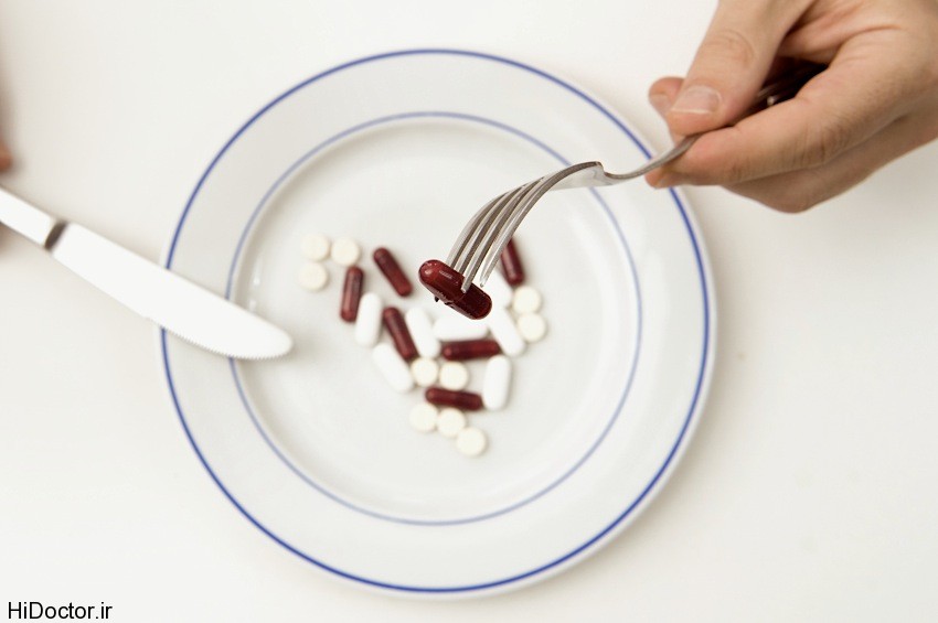 Medical Meal, Man hands with fork and Knife eating Tables and Pills on a plate