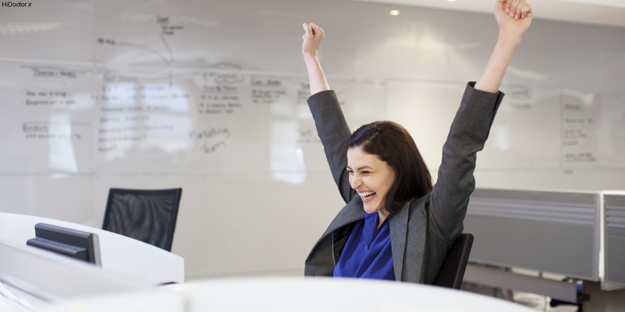 Enthusiastic businesswoman with arms raised in office