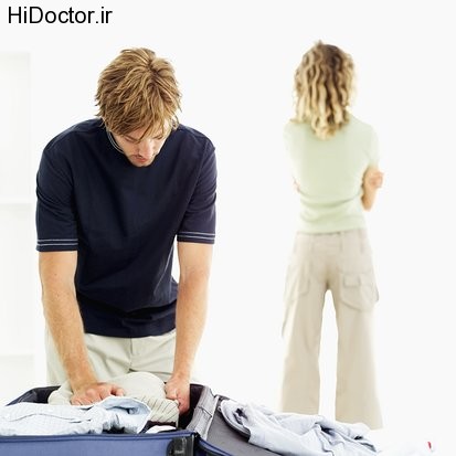 Close-up of a man packing a suitcase and rear view of woman in the background