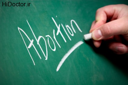 A hand writes the word "Abortion" on a chalkboard.
