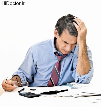 Man at desk in shirt and tie holding his head and worrying about money.