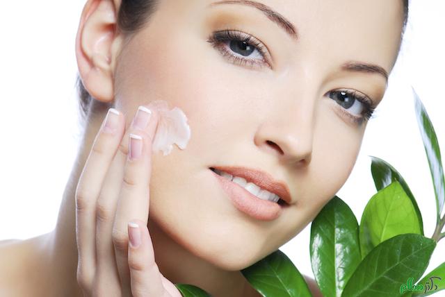 Woman applying moisturizer cream on face. Close-up fresh woman face.