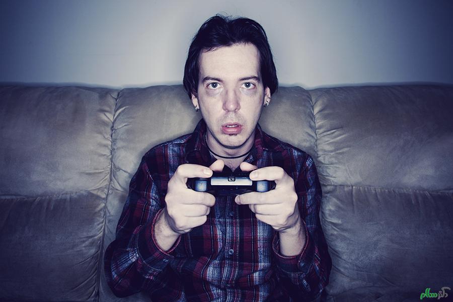 Man sitting on a couch playing video games in a dark room