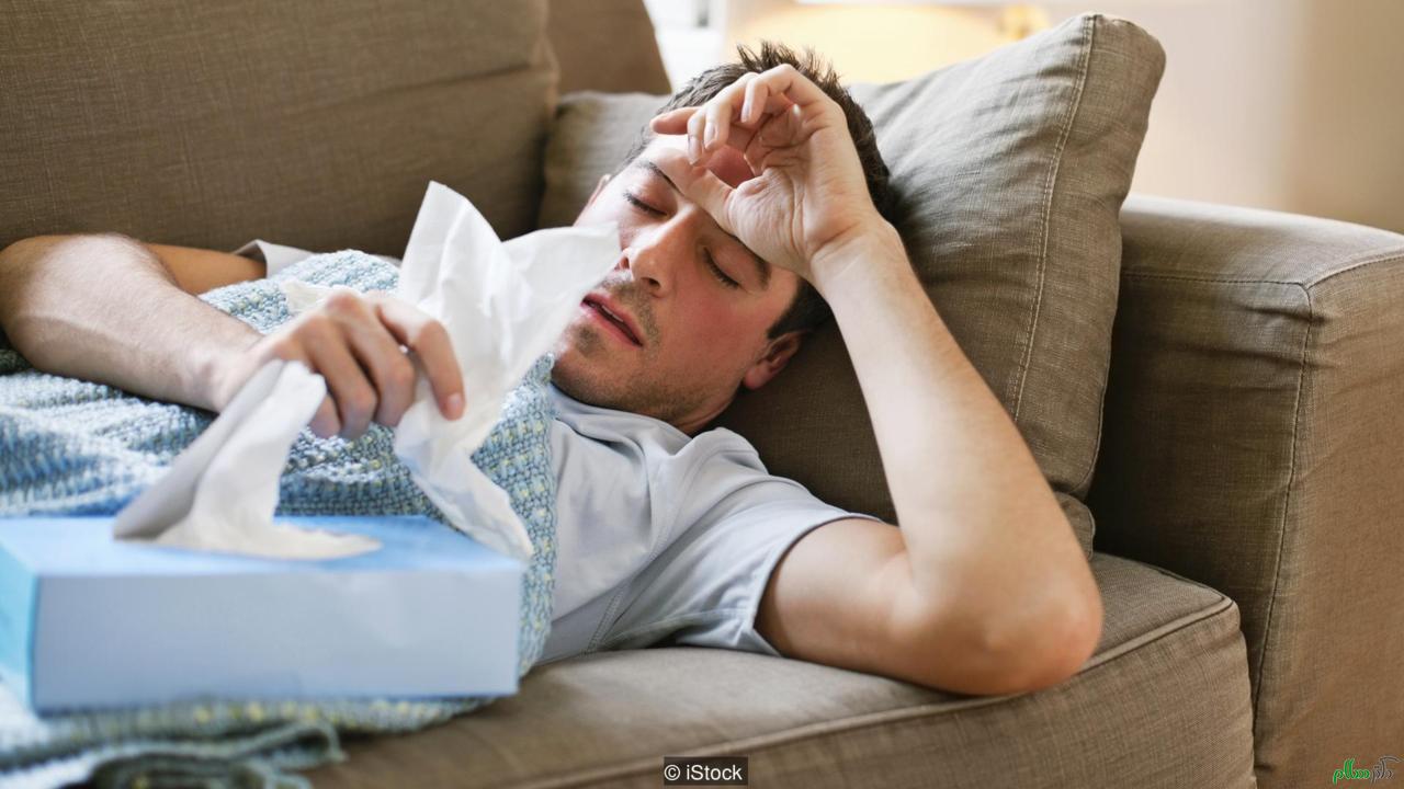 Man with a cold lying in sofa holding tissues