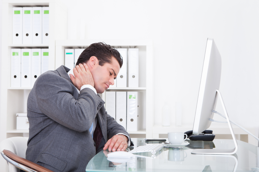Young Businessman In Office At Desk Suffering From Neck Pain